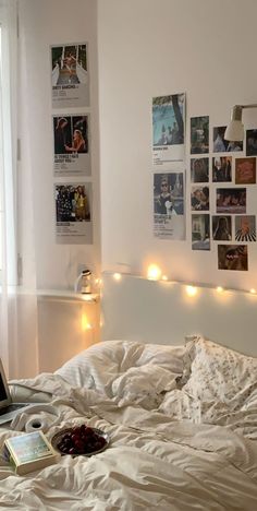 a laptop computer sitting on top of a bed covered in white sheets and blankets with lights strung from the headboard