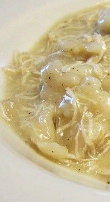 a white plate topped with pasta and meat covered in gravy on top of a table