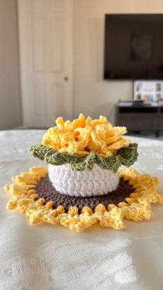 a crocheted sunflower sitting on top of a bed next to a flat screen tv