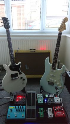 two electric guitars sitting next to each other in front of a guitar amplifier and amp