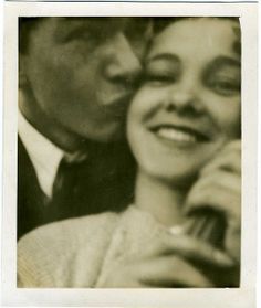 an old black and white photo of a man kissing a woman's face with her eyes closed