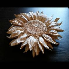 a large sunflower sitting on top of a wooden table next to a black surface