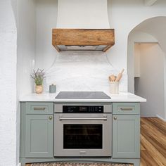 a stove top oven sitting inside of a kitchen next to a wooden floor and white walls