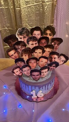 a birthday cake with the faces of many people on it and blue lights behind it