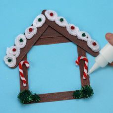 someone is making a gingerbread house ornament with candy canes and glue