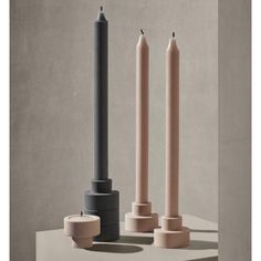 three candles sitting next to each other on top of a table with one candle in the middle