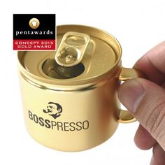 a hand is holding a gold can with the label bosspresso on it's side