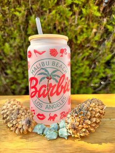 a can of beer sitting on top of a wooden table next to some pine cones