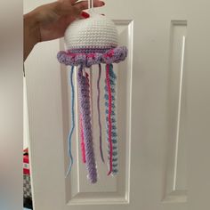 a hand is holding a crocheted object in front of a white door handle