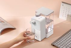 a person is holding a glass near a water dispenser on a desk