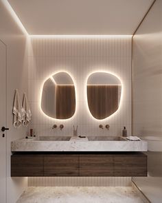 a bathroom with two round mirrors above the sinks and lights on the wall behind it