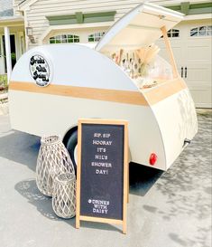 an old camper is parked in front of a house with a chalkboard sign next to it