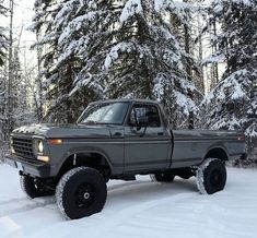 a truck is parked in the snow by some trees