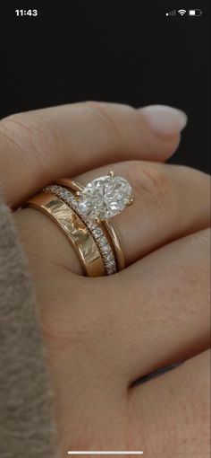 a woman's hand with two wedding rings on top of her finger and an engagement ring