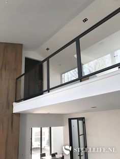 an empty living room with wooden floors and glass railings on the second story balcony