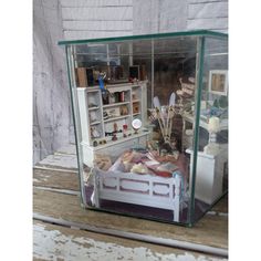 a doll house with a bed, desk and shelves in the middle on top of a wooden floor