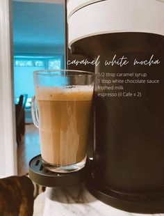 a cup of coffee sitting on top of a counter next to a milk dispenser