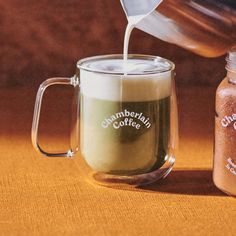 coffee being poured into a glass mug with ground coffee in the cup next to it