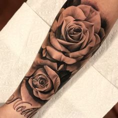 a black and white rose tattoo on the left arm, with words written in cursive writing