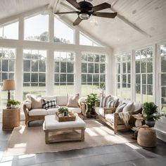 a sun room with couches, tables and lamps on the floor in front of large windows