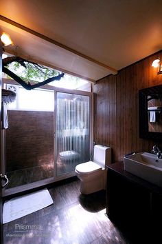 a bathroom with wood paneling and a glass door leading to the outside shower area