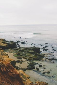 a person standing on the edge of a cliff near the ocean