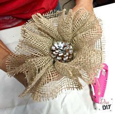 a person holding a piece of burlap with a pine cone on it's center