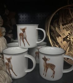 four white and brown deer mugs sitting next to each other on a black table