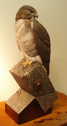 an owl statue sitting on top of a piece of wood