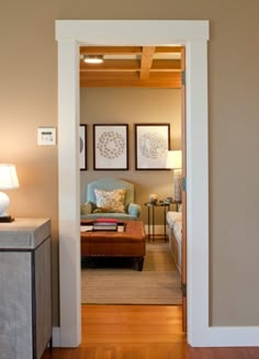 an open door leading to a living room with furniture and lamps on the side tables