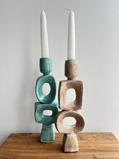 two candles sitting on top of a wooden table next to some blocks with holes in them