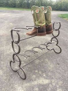 a pair of cowboy boots sitting on top of a metal stand with horseshoes in the shape of hearts