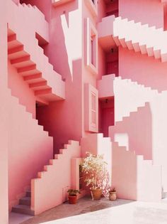 a pink building with stairs and potted plants