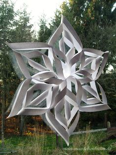 a large metal snowflake sitting on top of a lush green field