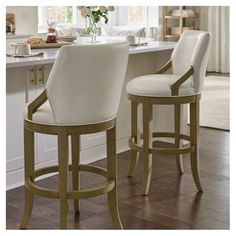 two white bar stools sitting in front of a counter