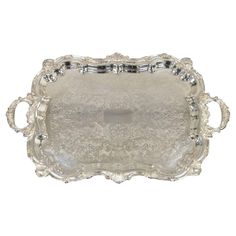 an ornate silver tray with handles and beading on the sides, set against a white background