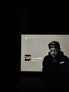 a laptop computer sitting on top of a black table with a screen showing the album all mine