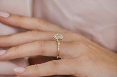 a woman's hand with a diamond ring on her left hand and the other hand holding an engagement ring