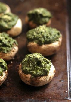 baked mushrooms with pesto on them sitting on a baking sheet