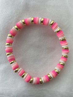 pink and gold beaded bracelet on white fabric with gold accents, close up view