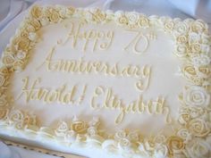 a sheet cake with white frosting and roses on it that says happy 70th anniversary