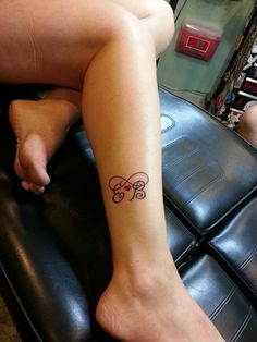 a woman with a tattoo on her leg sitting on a black leather chair in a room