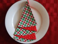 a white plate topped with christmas napkins on top of a red and green table cloth