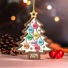 a wooden christmas tree ornament hanging from a string with ornaments around it on a table