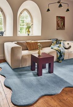 a living room filled with furniture next to two arched windows and a blue rug on the floor