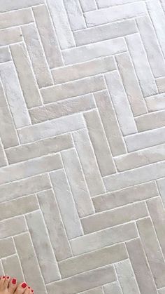 a woman with red nail polish on her toes standing in front of a white tile floor