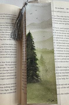 an open book with a painting on the pages and a tassel hanging from it