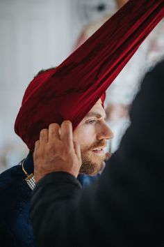 a man with a red turban on his head is looking at another man