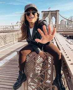 a woman sitting on top of a metal fence with her hand up in the air