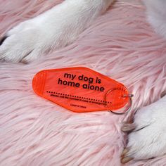 a keychain that says, my dog is home alone on a pink furry surface